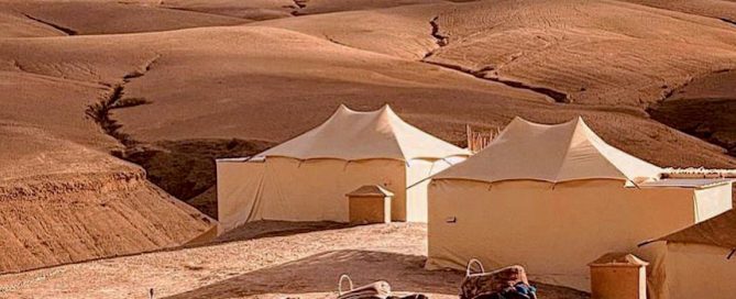 Tentes nomades au cœur du désert d'Agafay, avec un guide menant des dromadaires à travers les paysages arides.